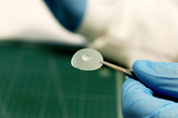 La investigadora Susana Guzmán sostiene un fragmento de este bioplástico a base de celulosa con una gota de agua sobre él, demostrando así su capacidad hidrófoba